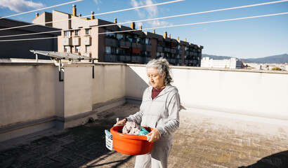 Elderly woman doing laundry on urban rooftop