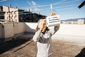 Senior woman doing laundry on urban rooftop