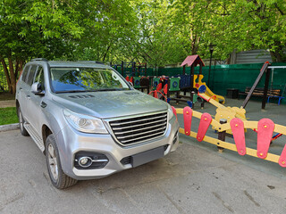 Silver car with the license plate . The car is parked in front of a children playground