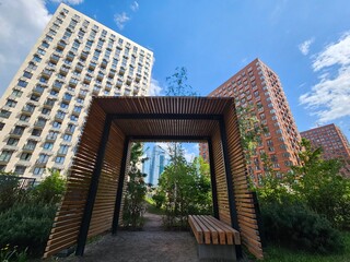 Wooden structure with a bench in front of a building. The bench is empty near entrance in the courtyard of the house in residential complex