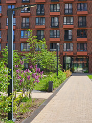 Brick building with a walkway in front of it. The walkway has a flower garden with purple flowers