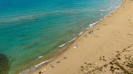 Aerial view of tourists on holiday on a beautiful sandy beach overlooking the Mediterranean Sea. This is Eloro beach, located in the Vendicari nature reserve in the province of Syracuse, Sicily, Italy
