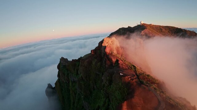 Flying over the clouds at Pico do Arieiro at sunset on the island of Madeira, Portugal. Magical sunset view above the clouds flying near mountain ranges and hikers.