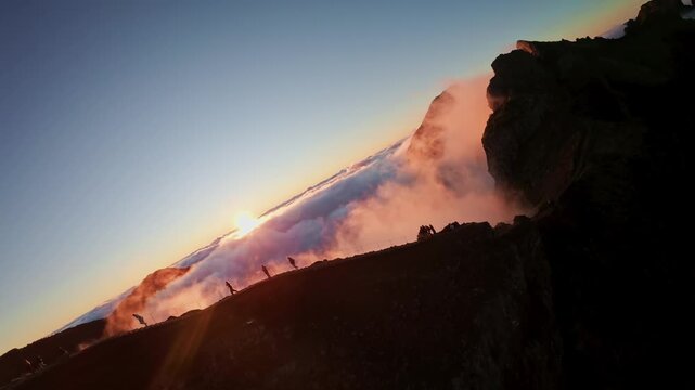 Flying over the clouds at Pico do Arieiro at sunset on the island of Madeira, Portugal. Magical sunset view above the clouds flying near mountain ranges and hikers.