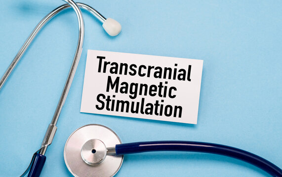 Transcranial Magnetic Stimulation on a white business card on a blue background with a stethoscope in composition in cold tones