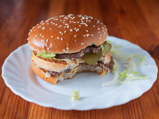 Delicious Half-Eaten Classic Double Cheeseburger on White Plate