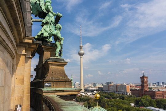 View of the golden angel statue atop a building with a backdrop of Berlin's TV Tower piercing the skyline under a bright sky, Mitte, Berlin, Germany.