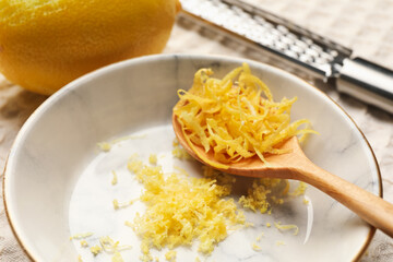Fresh lemons with zest and grater on tablecloth, closeup