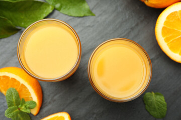 Fresh orange juice and fruits on black table, flat lay