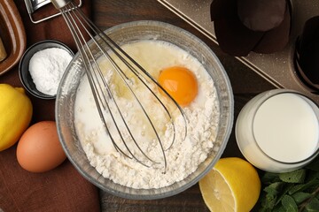 Ingredients for making muffins, whisk and cupcake tray on wooden table, flat lay