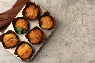Tasty muffins with raisins and mint on grey table, top view. Space for text