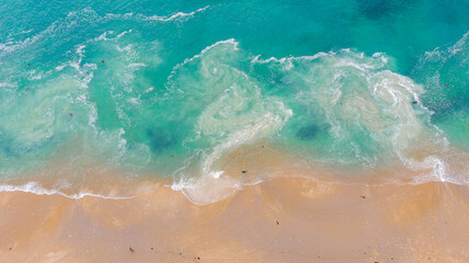 Aerial view of turquoise waves crashing onto the sandy shore of Hazards Beach, creating a mesmerizing dance of color and texture, Hazards Beach, Tasmania, Australia.