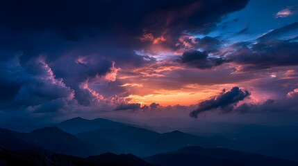 Dramatic, richly colored sunset illuminates turbulent storm clouds above layered mountain silhouettes