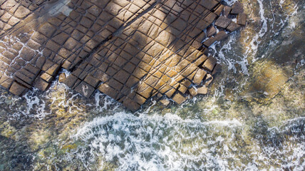 Aerial view of the geometric tessellated pavement meeting the turquoise sea, Tessellated Pavement State Reserve, Tasmania, Australia.