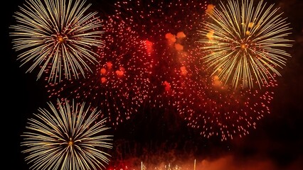 Vibrant bursts of gold and red fireworks light up the dark night sky during a celebration