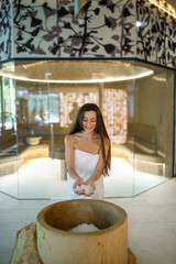 Excited young woman in a towel preparing for the spa salt therapy in spa center