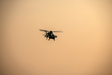 Silhouette helicopter is flying on isolated sky during dawn