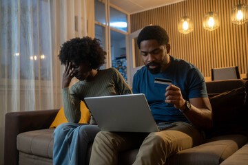 Stressed Woman Watching as Man Spends Money Shopping Online.