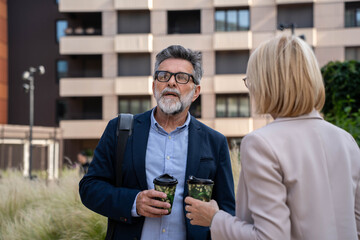 Business talk mixed with a little chit-chat. Shot of two businesspeople drinking coffee together outside an office.