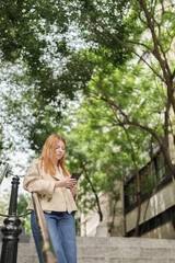 Young woman checking smartphone standing on urban stairs