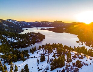 Aerial view of a mountain lake at sunset with snow-covered hills