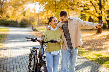 Couple enjoys a sunny autumn day cycling and laughing in a vibrant park setting