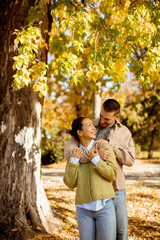 Joyful autumn walk under golden leaves with a couple enjoying nature together