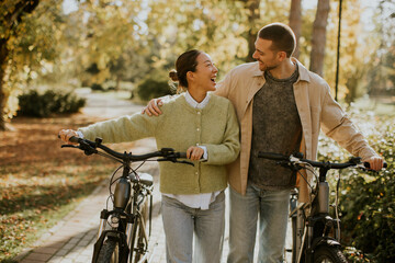 Korean woman and Caucasian man joyfully share a moment during a bike ride in a park