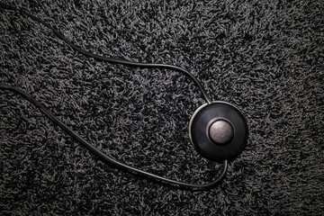 top view of a foot switch of a floor lamp on a long-pile carpet, all in black