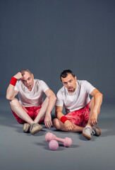Two funny fitness men are resting after training