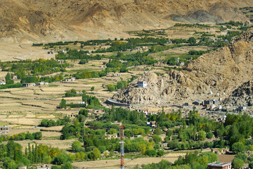Green agricultural land amongst barren mountains of Leh, Ladakh - image shot from Changla pass. Leh, Jammu and Kashmir, India