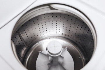 Fototapeta premium Empty washing machine drum interior. Stainless steel washer inside view. Clean laundry appliance. Modern household equipment. Minimal white design. Top view perspective. Domestic washing technology.