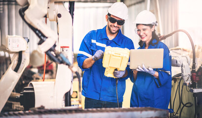 Engineers team mechanic using computer controller Robotic arm for welding steel in steel factory workshop. Industry robot programming software for automated manufacturing technology