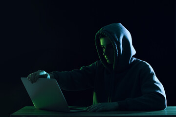 Hacker using laptop in dark environment representing cybercrime, hacking activity, data breach risk, online threat, and digital security vulnerability concept
