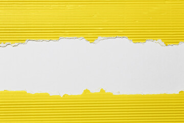 Torn yellow corrugated paper revealing white horizontal strip symbolizing attention grabbing message, strong contrast, copy space and creative design concept