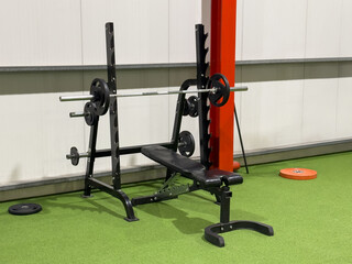 fitness equipment with barbell and bench in a gym