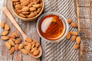 Honey in jar and almonds on wooden table, flat lay