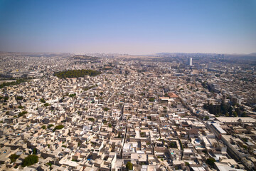 Obraz premium Wide aerial panorama of densely built city with tightly packed residential and commercial buildings stretching to horizon under clear blue sky. Sanliurfa, Turkey