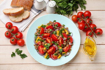 Delicious lentil salad and ingredients on light wooden table, flat lay