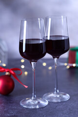 Glasses of red wine and Christmas decor on grey table