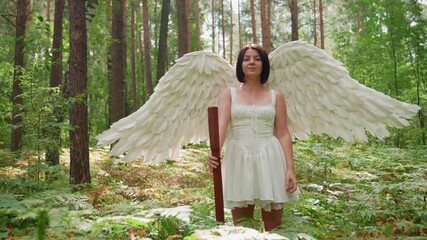 Forest guardian angel dressed in white with large feather wings holding wooden staff confidently lowering it among sunlit trees surrounded by glowing ferns and peaceful greenery