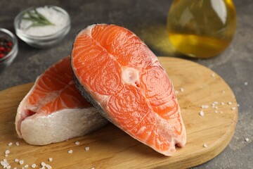 Pieces of salmon fillet with spices and oil on gray table, closeup