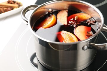 Tasty mulled wine cooking in pot on stove, closeup