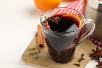 Mug with tasty mulled wine and ingredients on white wooden table, closeup. Space for text