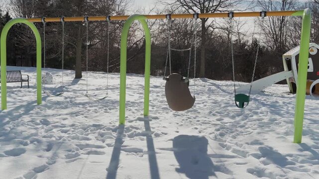 An empty playground with swings in snowy winter weather