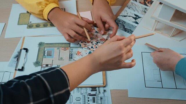 Two hands engage in a creative design process, sketching and arranging materials in a modern workspace, demonstrating collaboration and artistic inspiration. SACTR