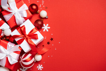 Red and white Christmas decorations and gifts on red background.