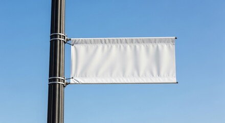 Obraz premium Blank white banner attached to a pole against a clear blue sky, offering space for advertising, announcements, or promotional messages