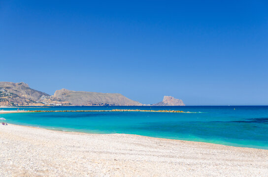Pebbe beach in Altea town on Costa Blanca coast, Morro de Toix mountain and Ifac rock, coastline Altea bay Mediterranean Sea with azure turquoise water in sunny summer day, Alicante province, Spain