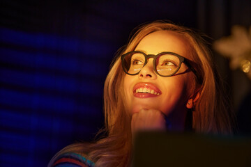 Blond cheerful woman using laptop and working late